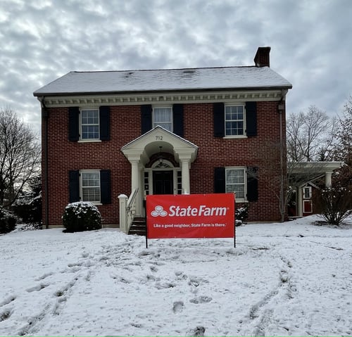 Brick building with black shutters and red State Farm sign out front