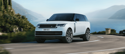 Fuji White Range Rover driving on a coastal mountain road