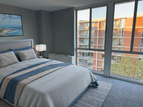 A bedroom with a large bed and a view of a building outside the window at The Langston Views Apartments in Washington, DC