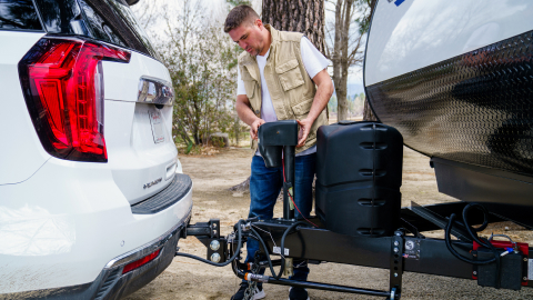 Man standing behind his vehicle that's attached to an RV with a hitch