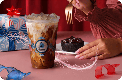 A festive scene with a Ho Ho Mint Mocha Espresso Shaker in a clear cup, a Chocolate Truffle Brownie on a white plate, and a gift-wrapped present.
