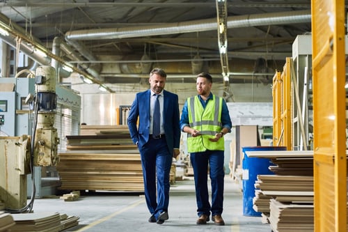business owner walking with employee in an industrial warehouse.