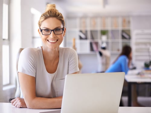 A woman working on a laptop in an office space.