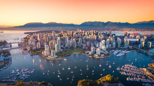 Downtown Vancouver at sunset with a view of False Creek and the North Shore mountains in the background.