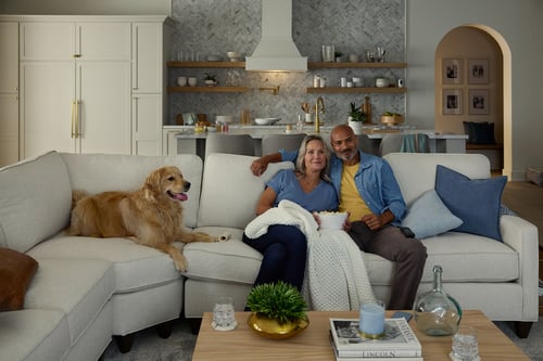 A couple sitting on the couch with their dog.