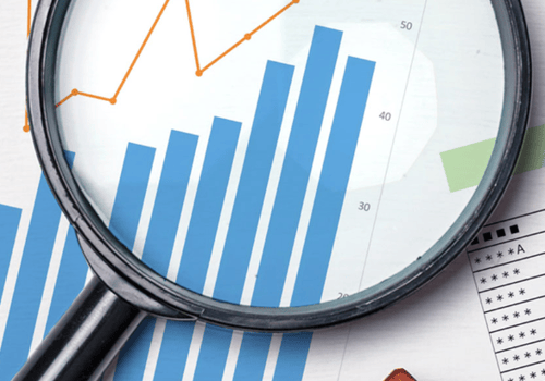 magnifying glass reviewing charts and graphs