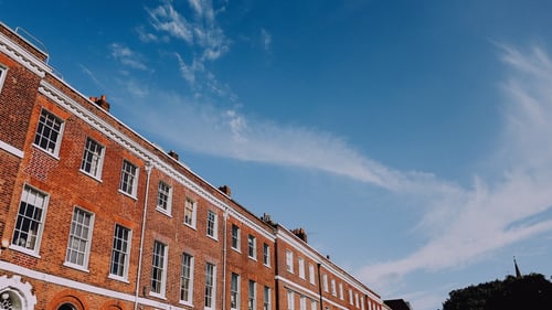 Row of tall period brick buildings against a blue sky