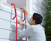 A man climbs down from his second story window using a Kidde Fire Escape ladder.