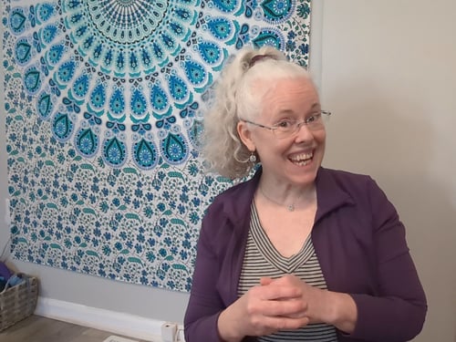 Yoga instructor smiling in front of tapestry