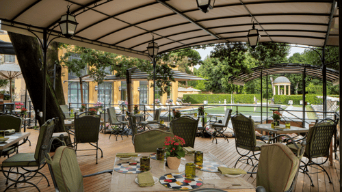Restaurant's tables in the shade of trees with the view of the city.