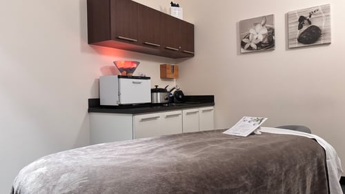 Luxury massage treatment room with a dressed table and warm lighting at Hand & Stone Spa in Ahwatukee, Phoenix AZ.