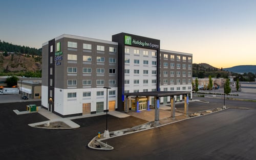 Hotel exterior at dusk with mountain views and parking lot.