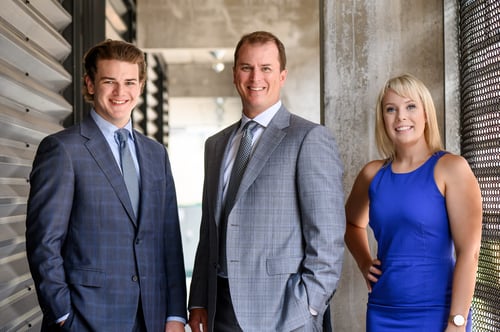 Carter in blue suit left, Kevin in grey suit middle, Emily in blue dress right standing in front of tunnel
