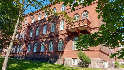 Punatiilinen rakennus ja vihreää nurmikkoa.