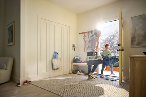 A mom and son evacuate their home with their pet in a carrier.