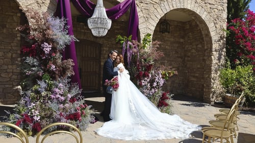 Bride and groom posing under a chandelier