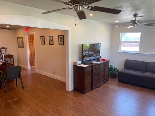 White walls with light wood floor and football on the tv
