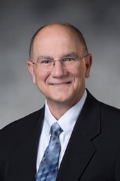 Dr. Wilde smiling in front of a gray background.