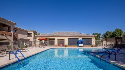A large blue swimming pool with a diving board and a building in the background at Sereno Townhomes in Glendale, AZ, 85302