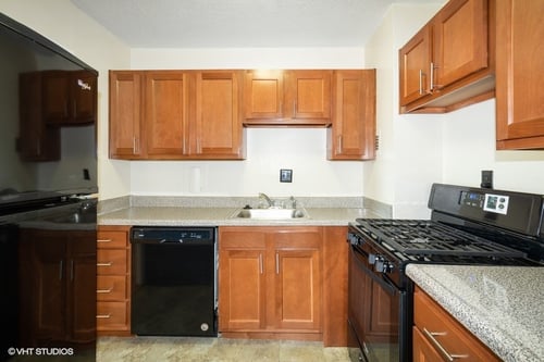 Kitchen in a standard unit with wood cabinets and black appliances.