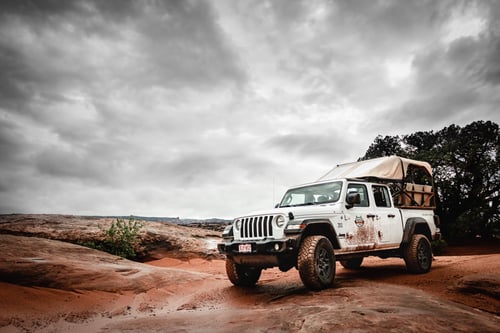 Jeep Gladiator driving through a rocky road in Moab Utah with cloudy skies