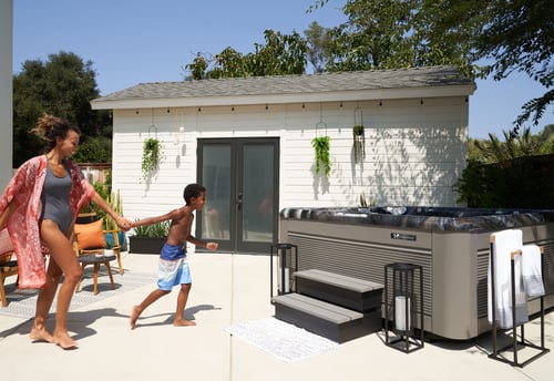 Caldera Vacanza hot tub, mother and son running toward backyard spa for outdoor water recreation