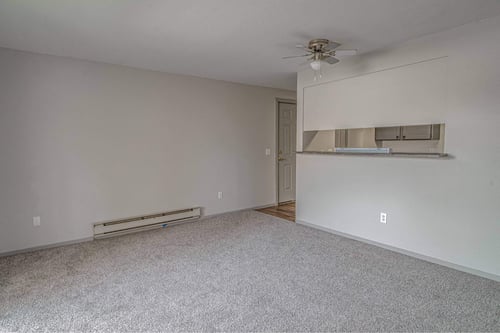 Empty room with a ceiling fan and a radiator on the wall.