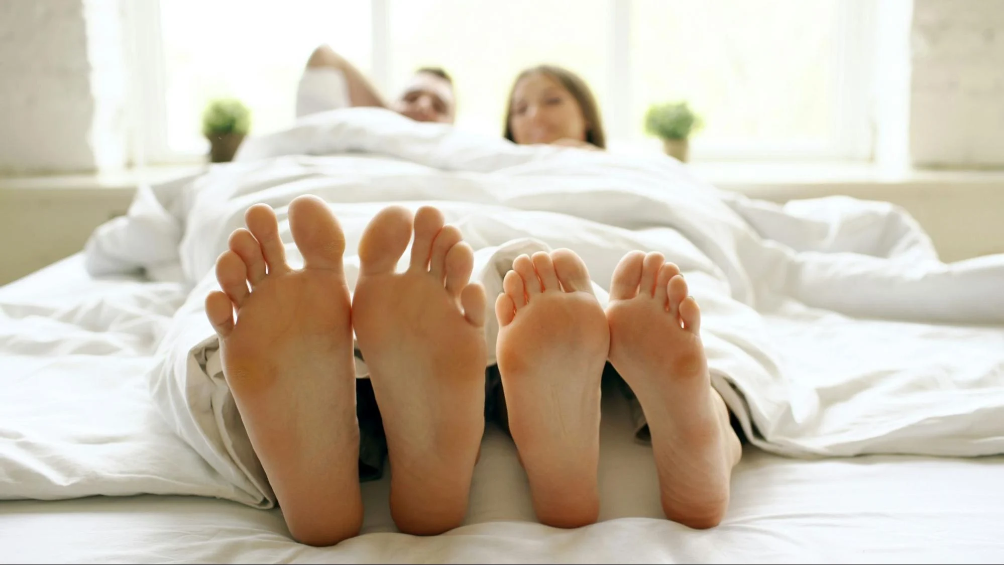 Couple in bed with their feet out of the covers