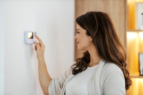 woman adjusting thermostat in home