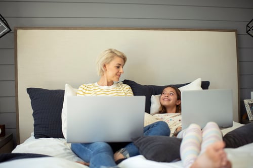 Mom and daughter using laptops in the bedroom