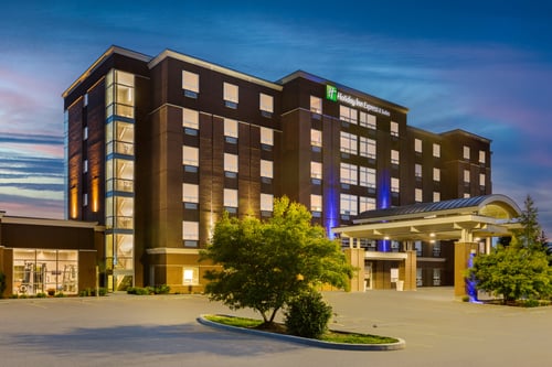 Hotel exterior at dusk with covered entrance and parking lot