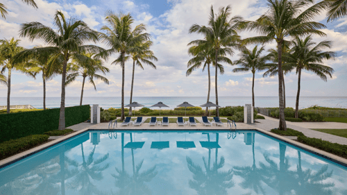 The Boca Raton Beach Club pool with palm trees on a partially cloudy day