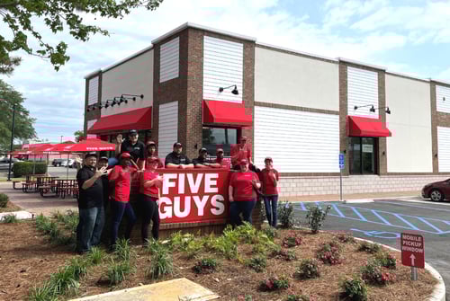Employees pose for a photograph around the exterior sign in front of the new Five Guys restaurant at 241 South Greeno Road in Fairhope, Alabama.