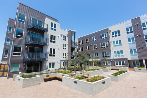 A modern apartment complex with a courtyard in the foreground.