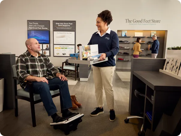 Una empleada de Good Feet Store hablando con el cliente que está usando el med massager