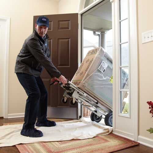 A Carrier dealer moves a furnace into a home as he performs an HVAC Installation