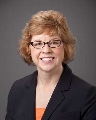 Patti smiling in front of a gray background