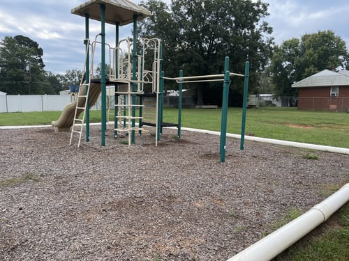 Colorful playground slide standing alone in the sunshine, set in an open play area.