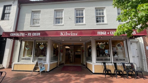 Exterior of the Kilwins Annapolis, MD 21401 chocolate, fudge, and ice cream store with doors opening wide onto a brick street