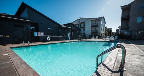 A swimming pool with a wooden deck and a metal railing at Eastpark Apartment Homes