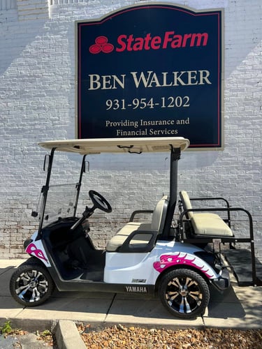 White brick building with black State Farm sign and golf cart parked out front