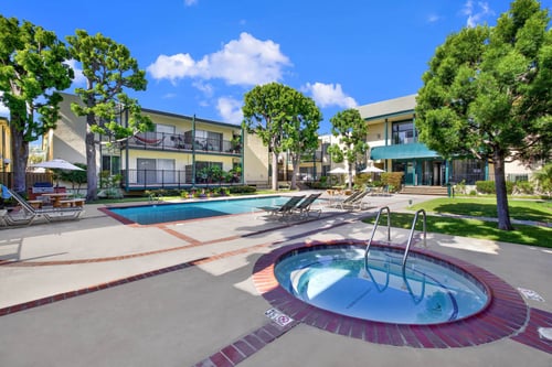a jacuzzi and swimming pool in front of an apartment building at Copa Ladeene Apartments, Torrance California