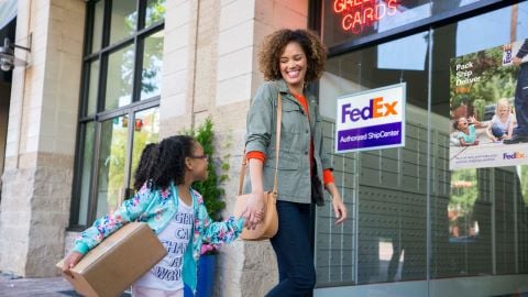 A woman and child entering a FedEx Authorized Ship Center