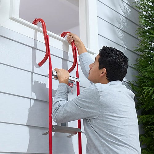 A man leaves his house from the window via a Kidde Escape Ladder