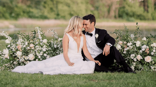 bride and groom sitting in front of a floral arrangement