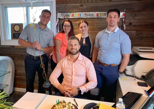 Agent Kris and four team members standing and smiling together in office