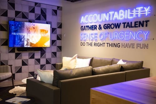 Salon confortable avec canapé et écran diffusant les valeurs de First Onsite.