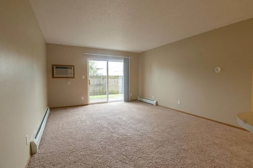 an empty living room with a sliding glass door at Peach Tree Apartments, Iowa