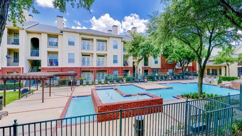 View of the gated resort style swimming pool and hot tub with lounge chairs at Montfort Place Apartments, Texas