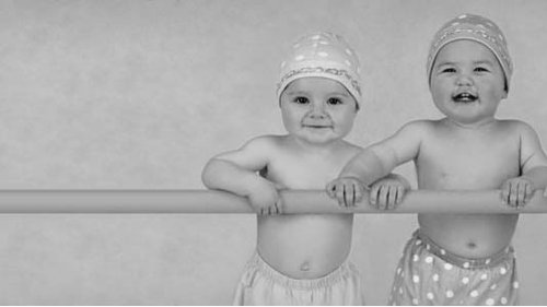 2 babies standing in a crib